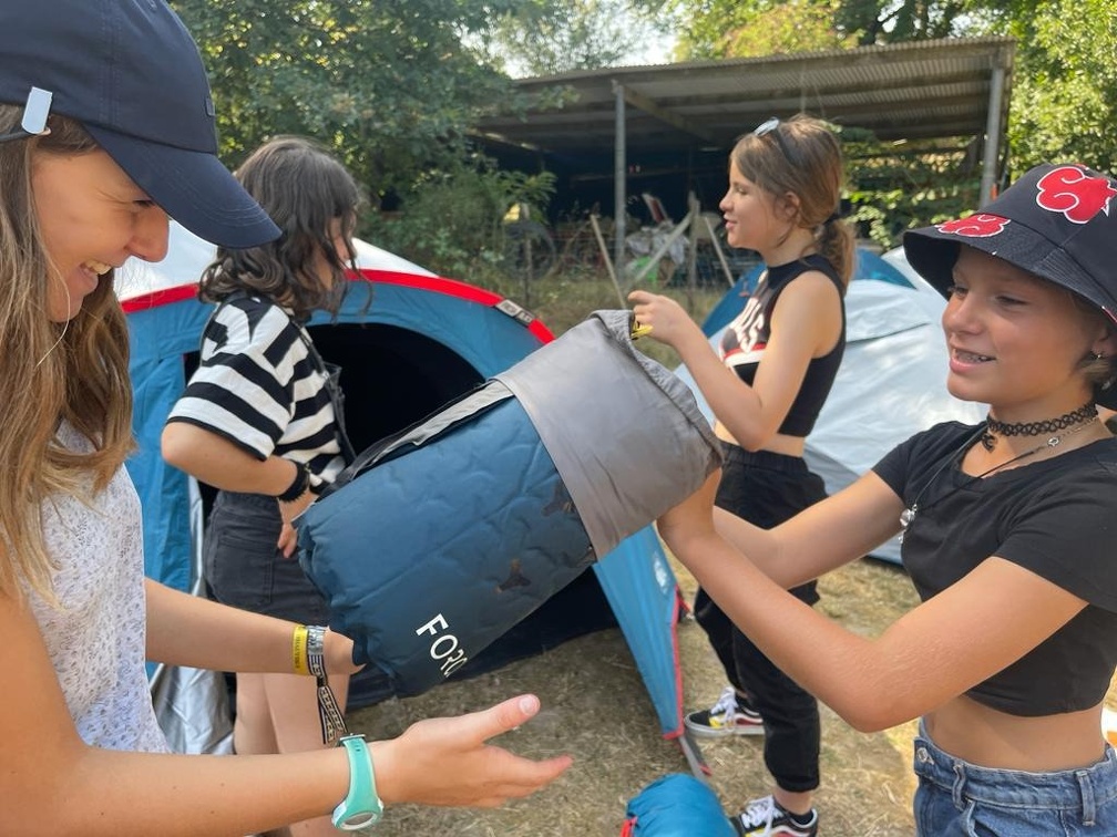 Photo d'enfants déballant un matelas de camping devant une tente